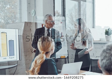 Confident businessman conducting a presentation while having staff meeting in the board room