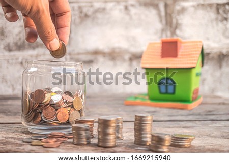 Drop coins into a glass bottle to save money for future investment, Concept for loan, mortgage, real estate investment, taxes and bonus, Saving money for the stability of the family in the future.