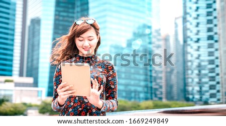 Young asian woman using electronic device at modern city  - Technology lifestyle concept with girl having fun with pc tablet device - Influencer digital trends on bright azure filter and sun halo Royalty-Free Stock Photo #1669249849