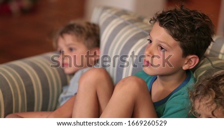 Candid kids on sofa watching movie entertainment at night time