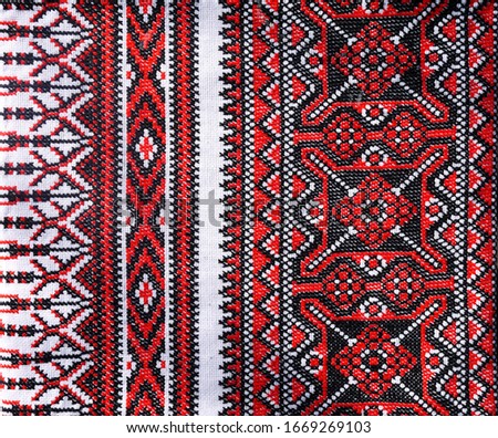 Ukrainian folk hand embroidery. Embroidered ornament with red-black threads on white fabric.