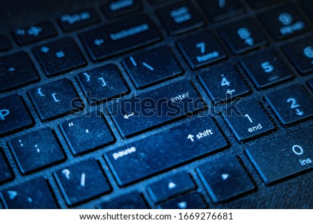 A deep blue black Picture of computer and laptop keyboard in close up with enter key in sharp focus
