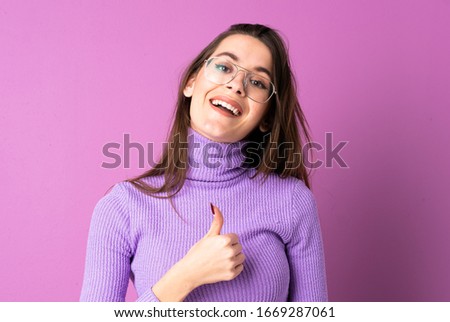 Young woman over isolated purple background giving a thumbs up gesture