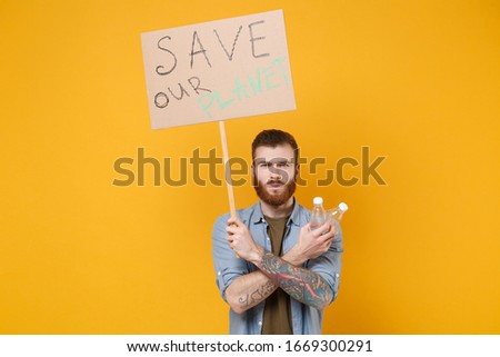 Displeased young protesting man hold protest sign broadsheet placard on stick, plastic bottle isolated on yellow background. Stop nature garbage ecology environment protection concept. Save planet