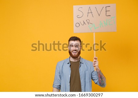 Funny young protesting man guy hold protest sign broadsheet placard on stick isolated on yellow background studio portrait. Stop nature garbage ecology environment protection concept. Save planet