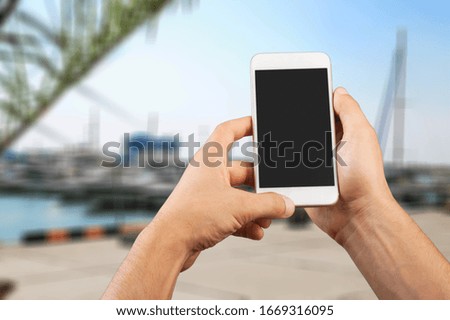 Human hands hold the smartphone with a blank screen