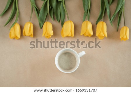 tulips in a row and coffee on craft paper. top view