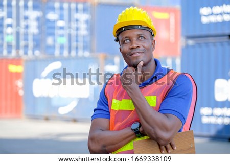 Portrait of African american technician man or engineer worker in cargo container factory stand and action of thinking. Concept of good system and manager support for better industrial business.