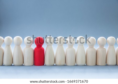 A row of human figures with a single individual standing out from the rest representing individuality and being different such as having a disease like coronavirus and infecting others Royalty-Free Stock Photo #1669371670