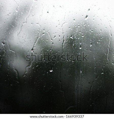 Rainy drops on the glass with the dark blurry background