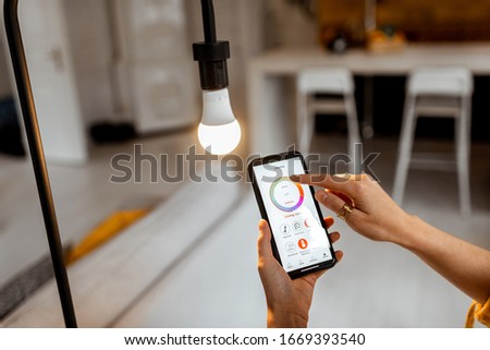 Controlling light bulb temperature and intensity with a smartphone application. Concept of a smart home and managing light with mobile devices