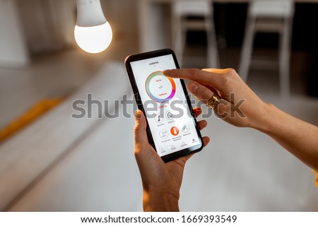 Controlling light bulb temperature and intensity with a smartphone application. Concept of a smart home and managing light with mobile devices