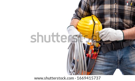 Electrician holds the roll of electric cable in his hand, helmet with protective goggles. Construction industry, electrical system. Isolated on a white background.