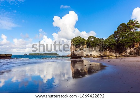 Great adventure for the rest of your life. Travel to New Zealand. Cathedral Cove. Ocean low tide. Mirror reflections of clouds in wet sand. The concept of exotic, ecological and photo tourism