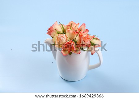 Kettle with roses on a blue background. Wishes good morning and have a nice day, minimal concept of holiday and spring. Greeting card, spring banner for the screen, happy birthday, wedding