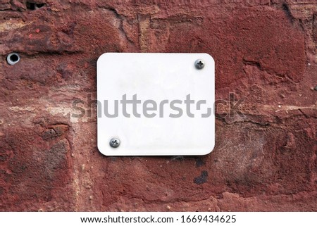 White House number plate with empty space for text mounted on a red painted brick stone wall.