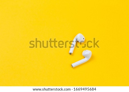White earphones on yellow background with copy space.