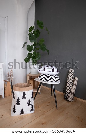 Scandinavian style interior: gray and white walls, wooden floor, monstera flower and different interior items.