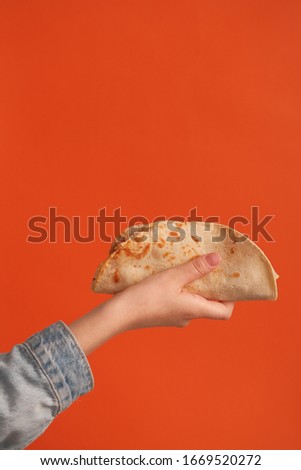 National food concept. Mexican national food tacos or Tatar national food - kystyby in hand on an orange background. Food in a tortilla. 