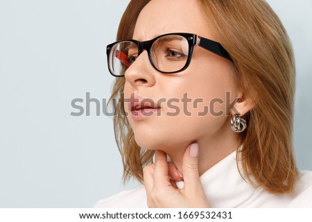 Close up of business woman touches fingers of sore throat over blue background. Thyroid gland, painful swallowing, tonsillitis, laryngeal swelling concept. Inflammation of the upper respiratory tract Royalty-Free Stock Photo #1669532431