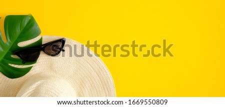 Summer sale banner design template. Top view beach hat, female sunglasses and tropical leaf on yellow background.
