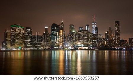 Great night view of the famous skyline of Manhattan downtown district with many skyscrapers, whose lights reflects in the water.