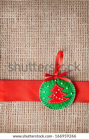 Christmas handmade toy with tree from felt on sackcloth background