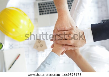 Close up top view of engineer and working people putting their hands together with stack of hands showing unity, teamwork and good cooperation in company.