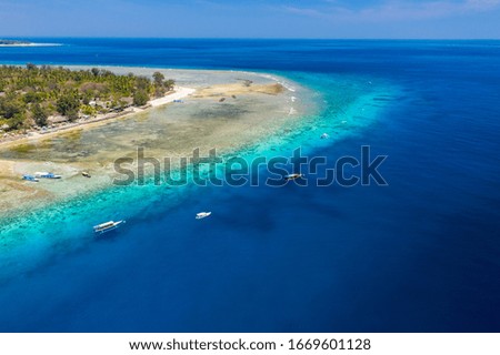 Aerial drone view of snorkelers and boats above a coral reef in a clear, tropical ocean