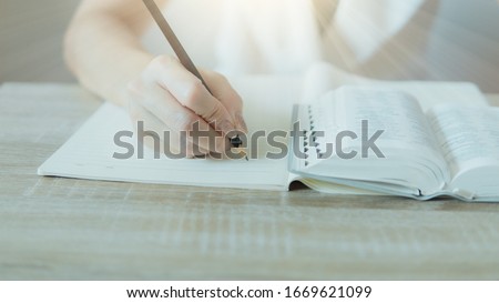Closeup of bible and woman hand holding a pencil and write something. Royalty-Free Stock Photo #1669621099