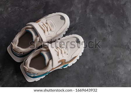 White sneakers on a dark grey background flat lay in minimal style. Trendy sports shoes, active lifestyle concept top view. Children training blog, teenagers kids workout.Copy space advertising banner