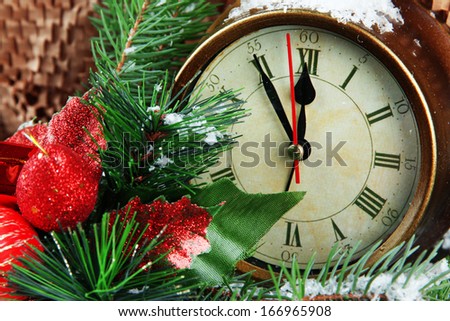 Clock with fir branches and Christmas decoration on brown background