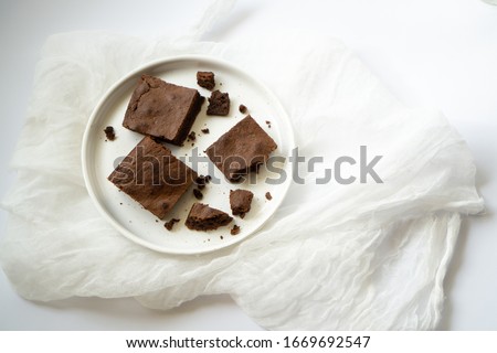 Close up of brownie pie bars with chocolate on a white plate. Top view of mouthwatering tortillas with crumbs. Copy space/