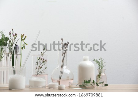 Herbal cosmetic products, laboratory glassware and ingredients on wooden table