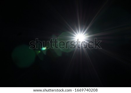 Lens Flare effect. White and blue light over black background. Abstract sun burst with bokeh. Easy to add overlay or screen filter over photos and images. Copy space. Star, space concept.