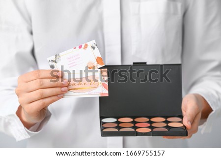 Woman with business cards of makeup artist and cosmetics, closeup