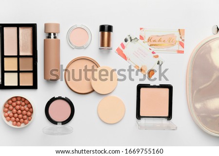 Decorative cosmetics with business cards of makeup artist on white background