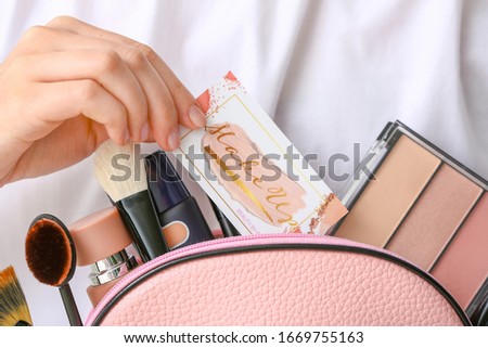 Woman with business card of makeup artist and cosmetics, closeup
