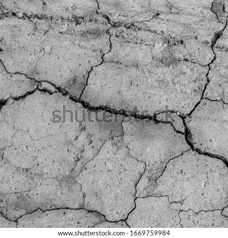 A high resolution old concrete cement with cracks and natural destruction from time and weather conditions. Non-color, monochrome black and white photo.