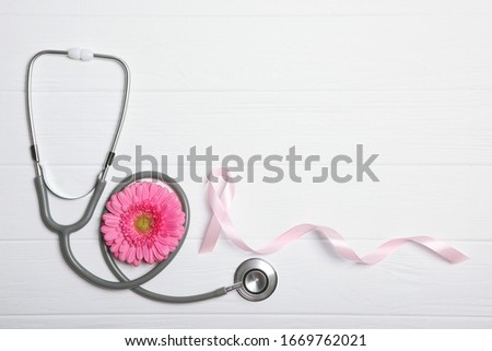 pink ribbon, gerbera and stethoscope on a colored background top view. Symbol of female cancer. Cancer Awareness in Women
