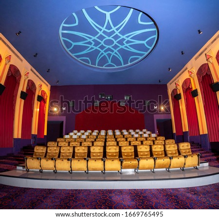Large cinema theater interior with seat rows for audience to sit in movie theater premiere by cinematograph projector. The cinema theater is decorated in classical for luxury feel of movie watching. Royalty-Free Stock Photo #1669765495