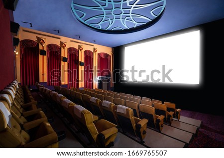 Cinema theater screen in front of seat rows in movie theater showing white screen projected from cinematograph. The cinema theater is decorated in classical style for luxury feeling of movie watching. Royalty-Free Stock Photo #1669765507