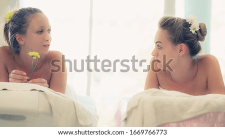 Two women at massage room having conversation in luxury day spa. Wellness, leisure and healthcare concept.