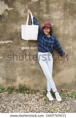Happy young asian girl carring Cloth bags and notebook at University.