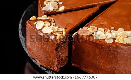 Modern pastry. Chocolate cake with nuts, almonds and peanut butter. Cake on a black background. background image, copy space text