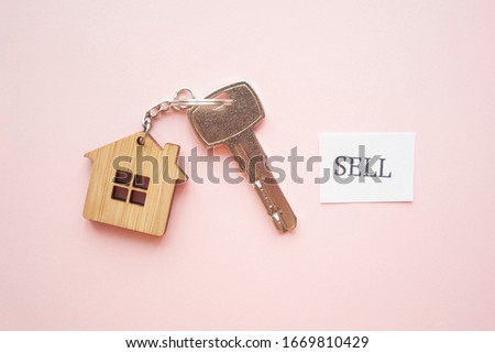 Wooden house toy and silver key on bright pink background with phrase quote Sell. Mortgage, house buy sell, investment, rent, realtor concept