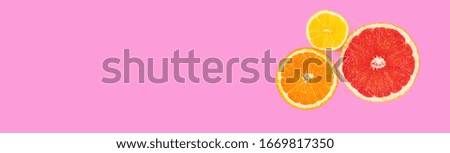 Slices of orange, pink grapefruit and lemon fruits on pink background. Top view of halves of citrus fruits. Banner