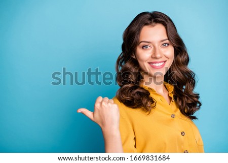 Photo of charming business manager lady indicating thumb finger empty space advising new product low price wear yellow shirt isolated blue color background