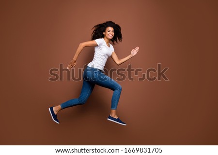 Full size profile photo of amazing dark skin lady jumping high sports competitions rushing finish line winner mood wear casual white t-shirt jeans isolated brown color background