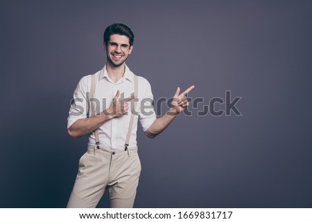 Photo of attractive macho business man indicating fingers empty space good news dressed formalwear white shirt beige suspenders trousers specs isolated grey color background